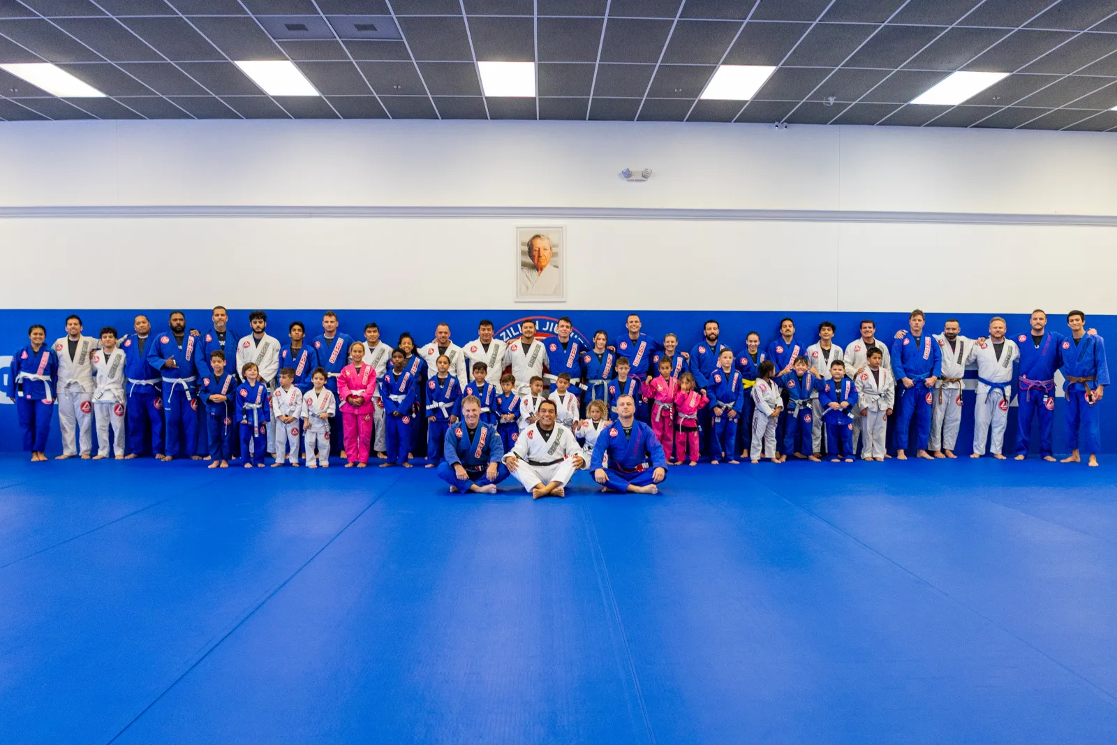 Adults and kids lined up for a Gracie Barra Davenport family group photo at the end of a belt promotion ceremony