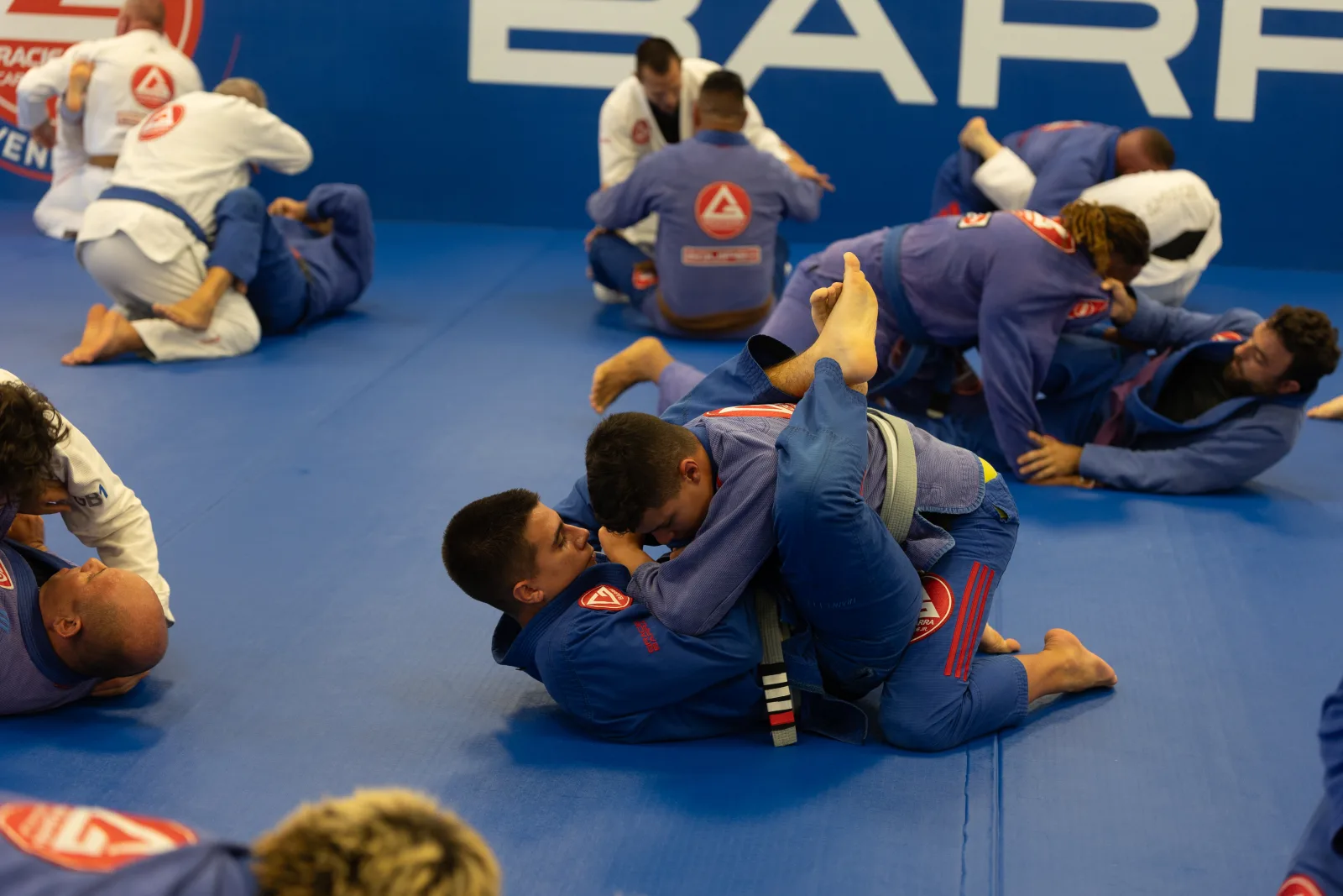Multiple pairs of students rolling Brazilian Jiu-Jitsu during open mat at Gracie Barra Davenport